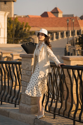 a lady in a beige blazer, a beige vest and a white dress with polka dots
